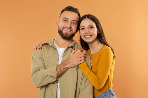 istock Happy Young Couple Hugging And Holding Hands Over Orange Background 2060390218