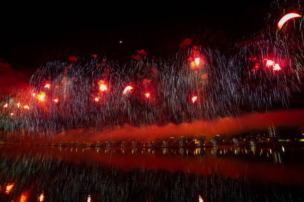 The multicolored bouquets sparkle in the sky and are reflected in the water of the pond.