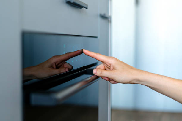 Cropped view on woman hand press sensor button of electric oven
