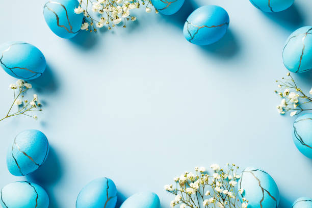 istock Frame of Blue Easter eggs with marble effect and flowers on light blue table top view. 2060469743