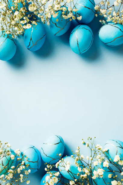 istock Painted Easter eggs and delicate flowers on a blue background. Top view, vertical, flat lay. 2060472390