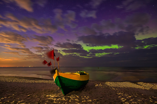 Northern lights over the Baltic Sea on the beach in Jantar with fishing boats, Poland.