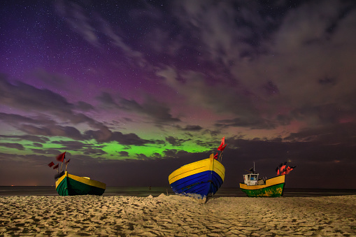 Northern lights over the Baltic Sea on the beach in Jantar with fishing boats, Poland.