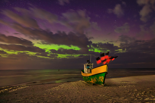 Northern lights over the Baltic Sea on the beach in Jantar with fishing boats, Poland.