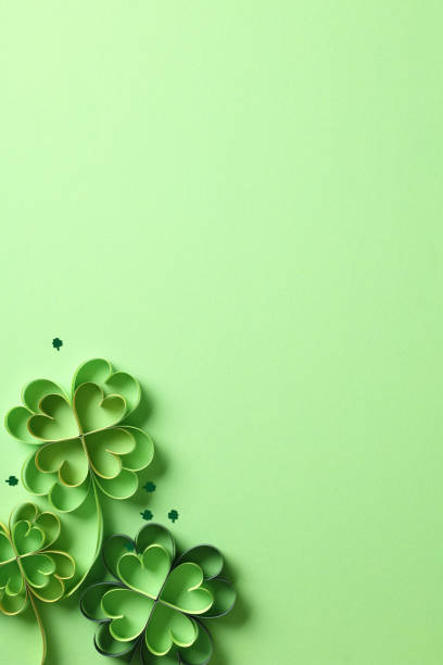istock St Patrick Day vertical banner design with paper art four-leaf clover and confetti on green background. Top view, flat lay. 2060494408