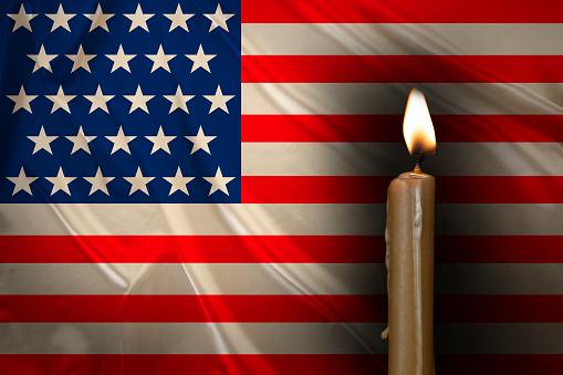 mourning candle burning front of flag USA, memory of heroes served country, grief over loss, national unity in challenging times, state's history