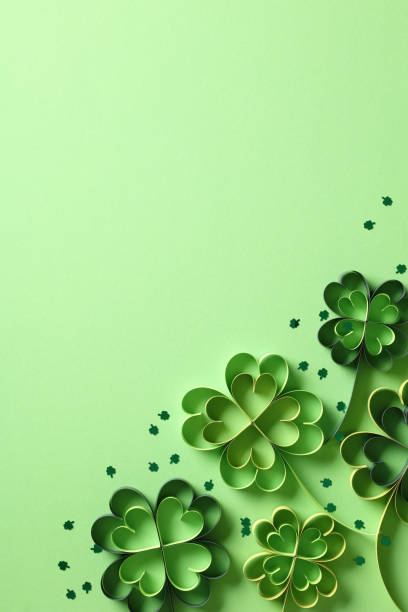 istock St Patrick's day vertical background with paper cut clover leaves and confetti on green background. 2060502397