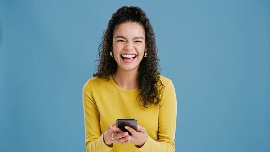 Woman, studio and phone to laugh for social media, online and funny joke on internet or blog. Female person, mockup space and app for silly conversation on blue background, browse and web for comic