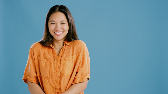 Woman, portrait and happy for style in studio, mockup space and casual clothes on blue background. Asian female person, smile and cool clothes for aesthetic, satisfaction and confidence for outfit