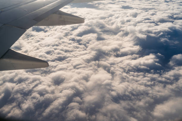 View from the airplane window mid air above clouds.