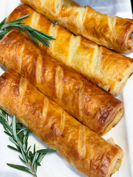 Full frame image of hotel self service buffet display, salad bar white serving plate of rows, golden brown, fresh crunchy sausage rolls, restaurant buffet, elevated view