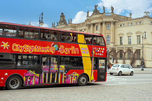 red open-top tourist bus, full of tourists driving through streets of Berlin, landmarks sightseeing tour, Discovering Berlin, Germany - February 19, 2024