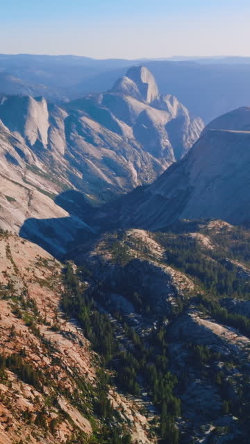 Grey rocks lit with bright sun. Mountainous landscape of Yosemite National Park, California, USA from bird's eye perspective. Vertical video