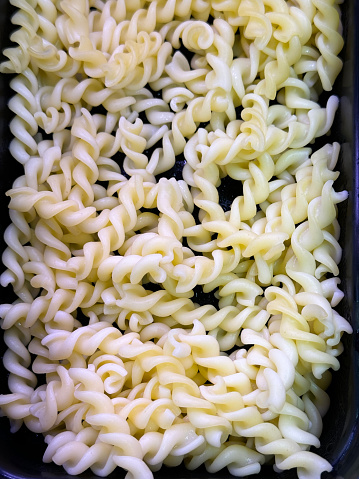 Stock photo showing close-up, elevated view of cold cooked pasta twists in a metal serving tray as part of hotel self service refrigerated buffet display.