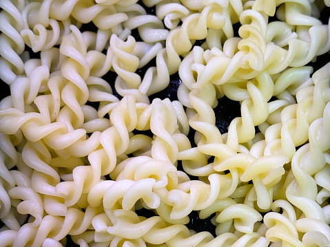 Stock photo showing close-up, elevated view of cold cooked pasta twists in a metal serving tray as part of hotel self service refrigerated buffet display.
