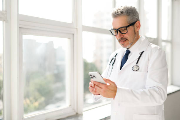istock Experienced confident senior doctor with grey hair using smartphone 2060619188