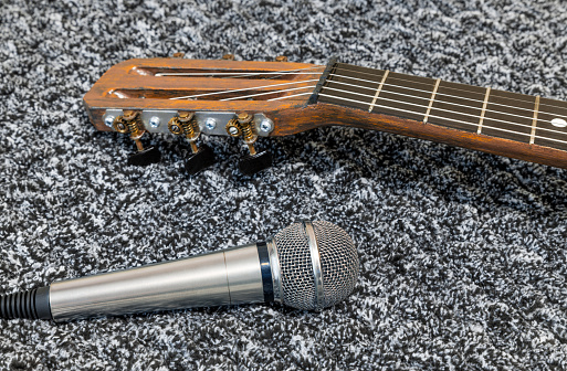 Acoustic retro guitar and microphone. Musical string instrument on soft cloth. Sound recording concept.
