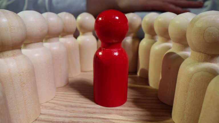 Red figurine of leader stands in oval of models of human