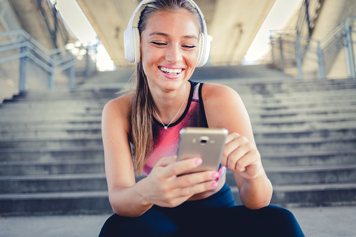 Fitness, music and headphones with young woman and phone for search, social media or internet. Workout, exercise and health with girl listening to music for sports training.