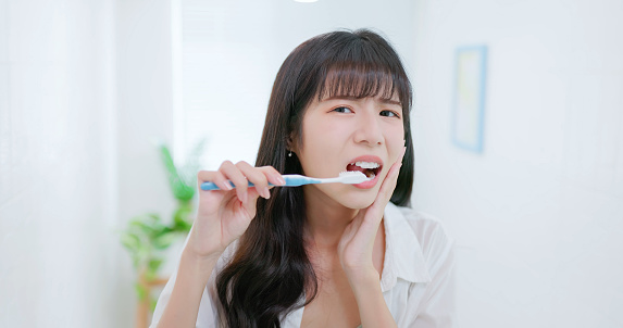 Closeup point of view asian woman feels tooth ache and uncomfortable when brushing her teeth at bathroom