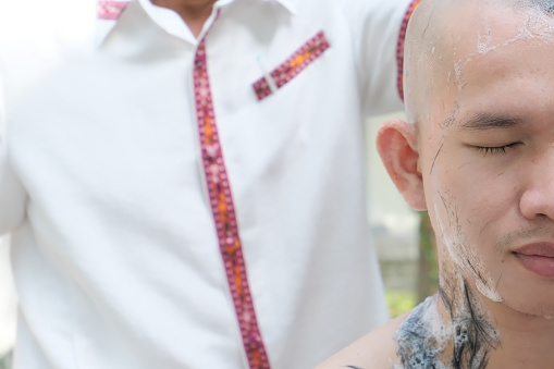 Portrait of a ceremonial head shaving ceremony for a man about to be ordained as a monk.
