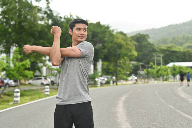 Millennial Asian man, Athlete fit man stretches his arm, Warm up before getting ready to work out or cool down after done, Activity healthy lifestyle concept.