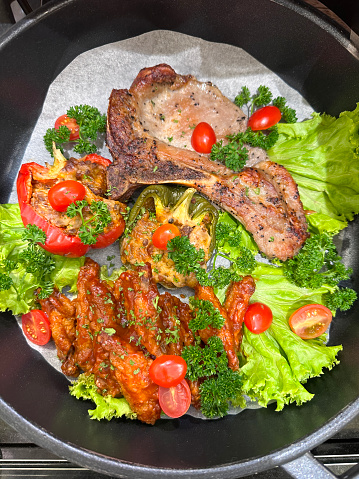 Stock photo showing elevated view of a meal of Chinese pork chop salad being served in a handled, metal cooking pot lined with greaseproof paper.