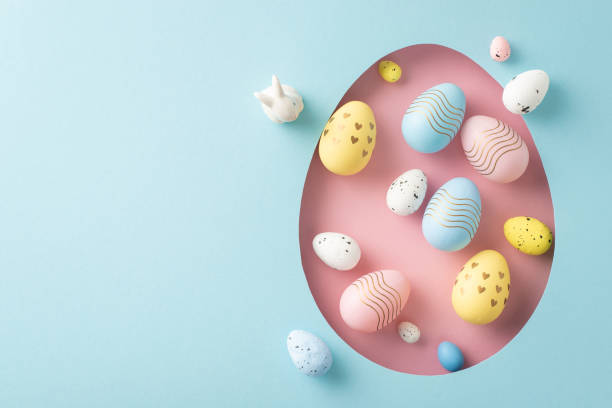 istock Greetings for Easter creativity theme. Top view shot featuring dyed eggs, showcased through a pink egg silhouette on a pastel blue surface, with a blank area for text or promo 2060685020