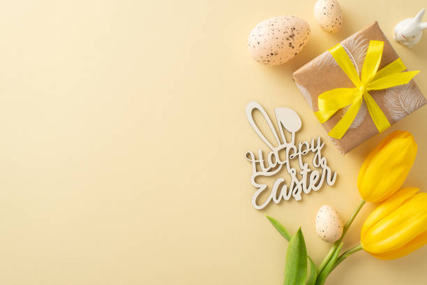 istock Charming Easter setup concept. Overhead view of kraft paper wrapped gift, yellow tulips, Happy easter greeting, Easter hare figurine, quail eggs, arranged on a light beige surface with space for copy 2060685065