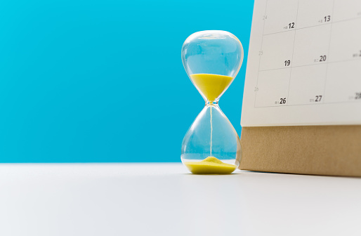 Calendar and hourglass on the table.