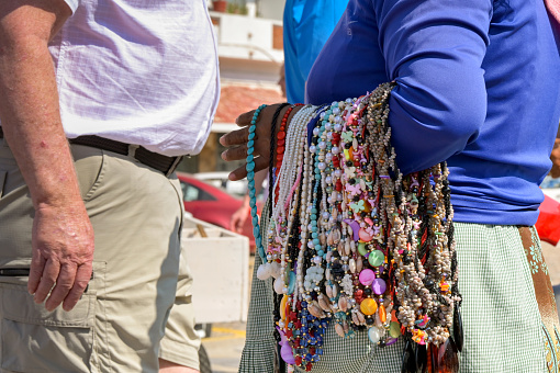 Acapulco, Mexico - 17 January 2024: Street trader with necklaces around her arm talking to a tourist.