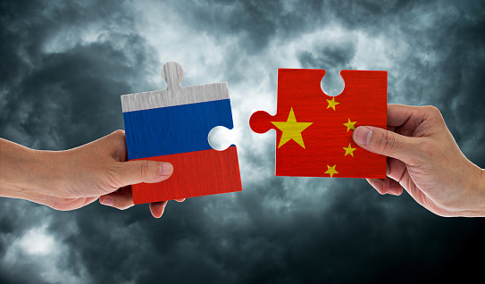 Hand holding Russia and China flags on puzzle pieces joining together