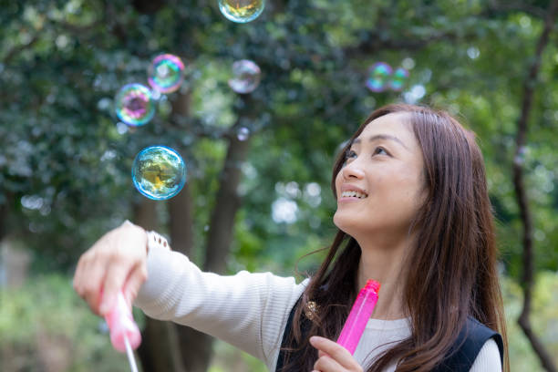 istock Woman playing with soap bubbles in public park 2060732372