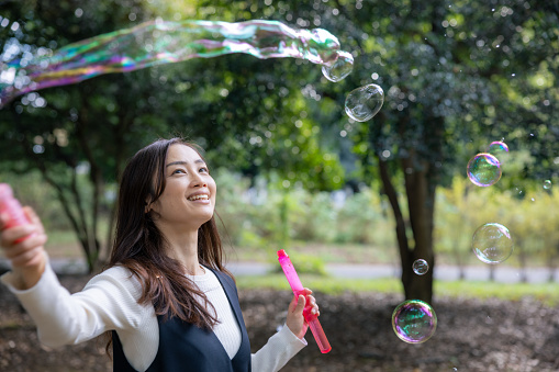 Woman playing with soap bubbles in public park