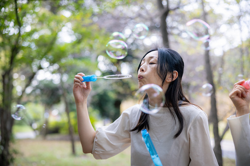 Female friends blowing soap bubbles in public park