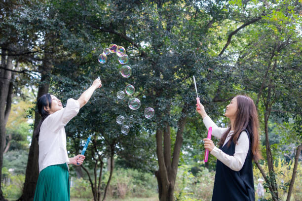 istock Female friends playing with soap bubbles in public park 2060733961