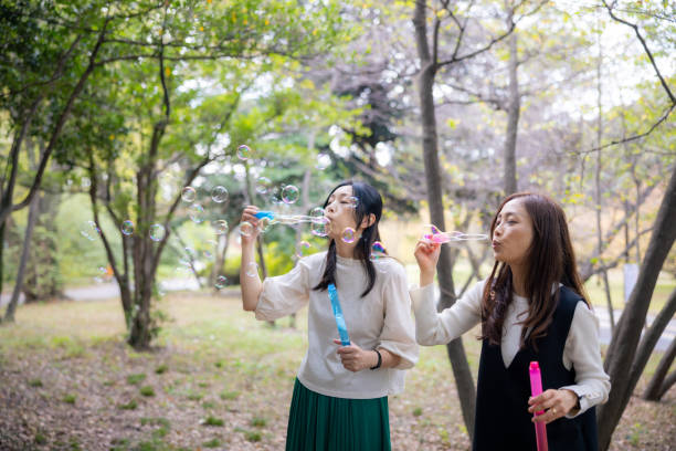 istock Female friends blowing soap bubbles in public park 2060734203