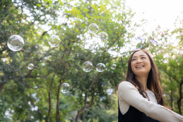 istock Woman playing with soap bubbles in public park 2060734559