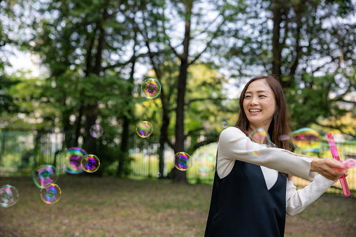 Woman playing with soap bubbles in public park