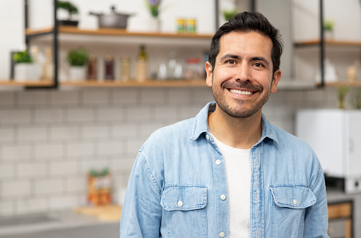 Portrait of a Latin American man smiling in the kitchen at home and looking at the camera