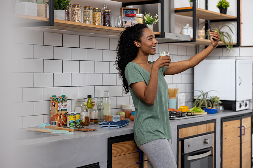 African American health influencer taking a selfie drinking a green smoothie at home