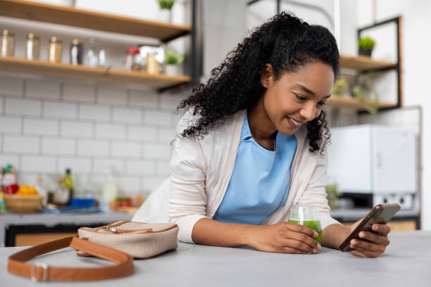 istock Nurse drinking a green juice while checking social media on her cell phone at home 2060737356