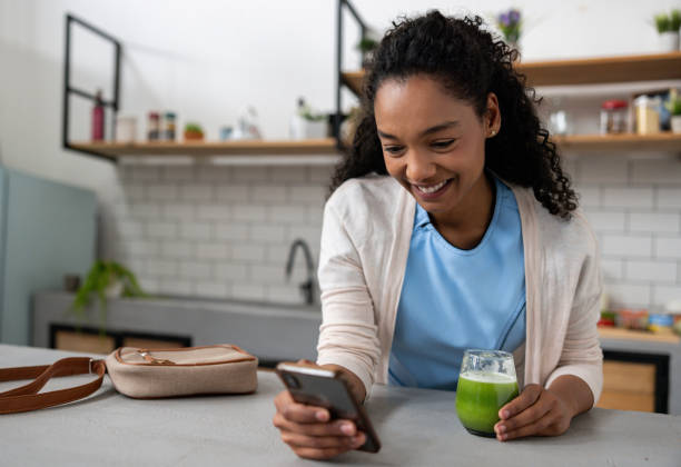 istock Nurse drinking a detox smoothie at home while checking social media on her cell phone 2060737372