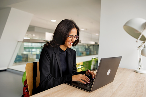 Smiling young woman works on laptop in the office