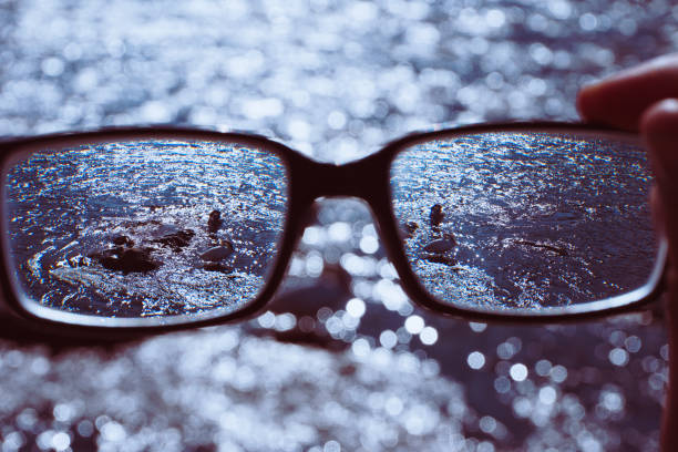 Cropped hand holding glasses against water