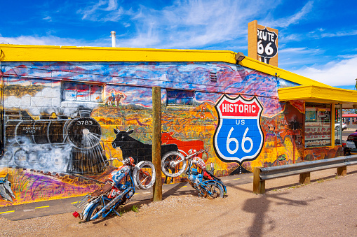 Seligman, Arizona, United States - September 22, 2023:  Mural on Gift Shop and partially buried motorbikes