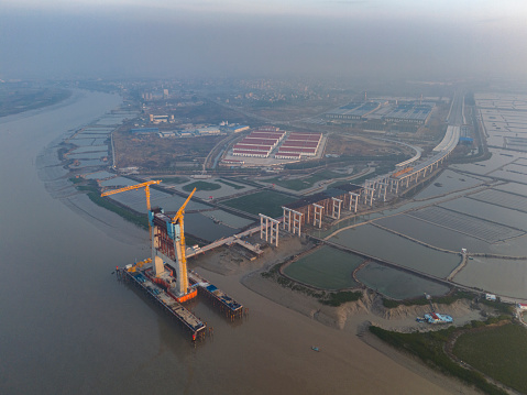 At sunrise, the tower crane of the under construction cross sea bridge is working