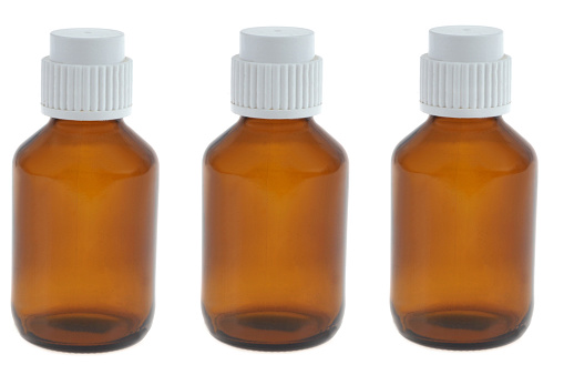 Glass bottles with white plastic caps close-up on white background