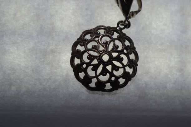 Magic pendant with an amethyst crystal on an atmospheric natural background, vertical format, selective focus. Witchcraft, mojo, amulet, promo, handmade, jewelry concept.