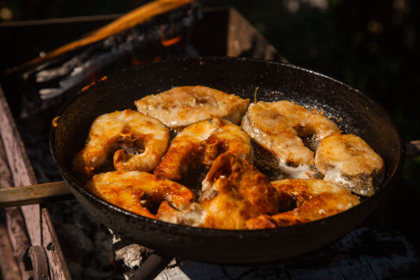 Pan with frying fish steak on the fire. Outdoor kitchen. Summer barbeque and vacation.